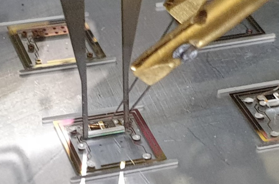 Automated assembly of small (9x9x1.7) mm³ laser packages with appropriate lenses and optical edge windows on panel-level prior to stacking, hermetic sealing, and subsequent laser-based singulation.